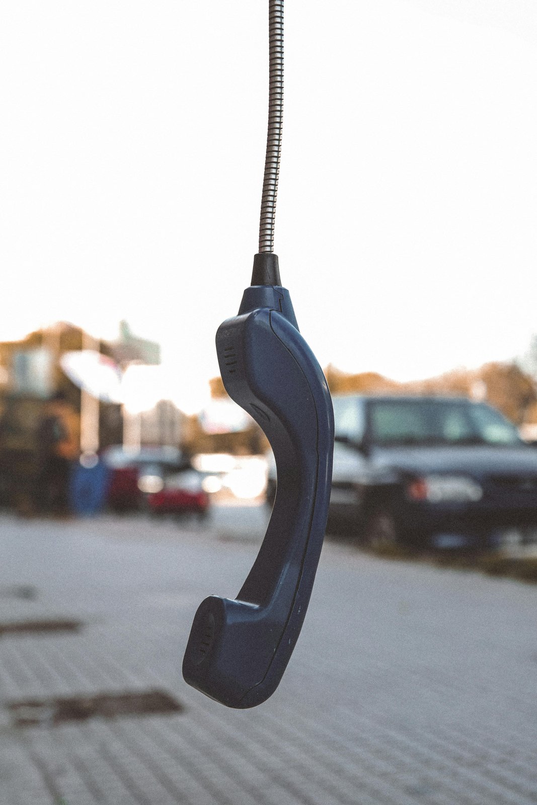 A receiver dangling on its cord at dusk — a quiet image of connection severed