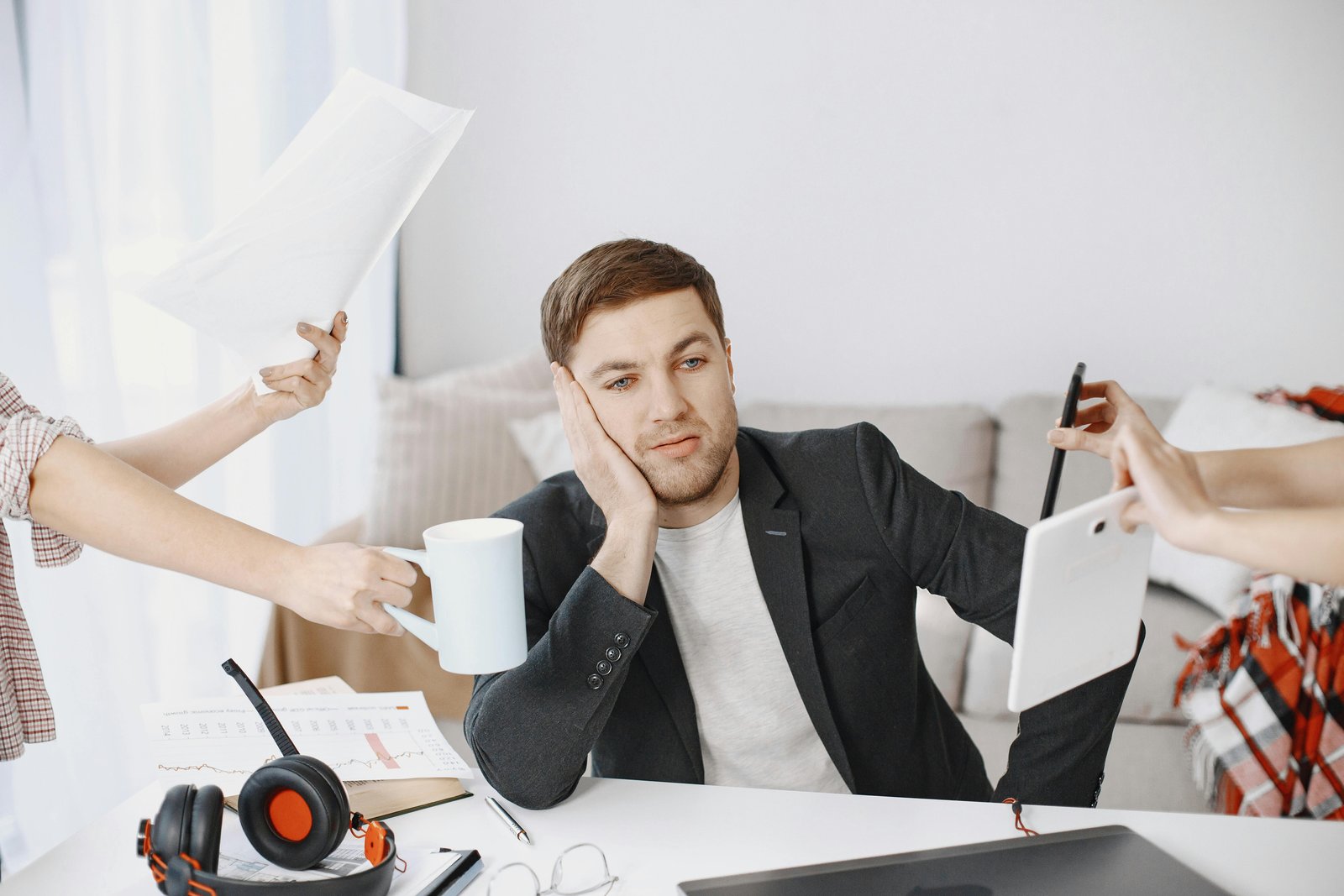 An agent at a desk, hands pressing in from every side — too many demands at once