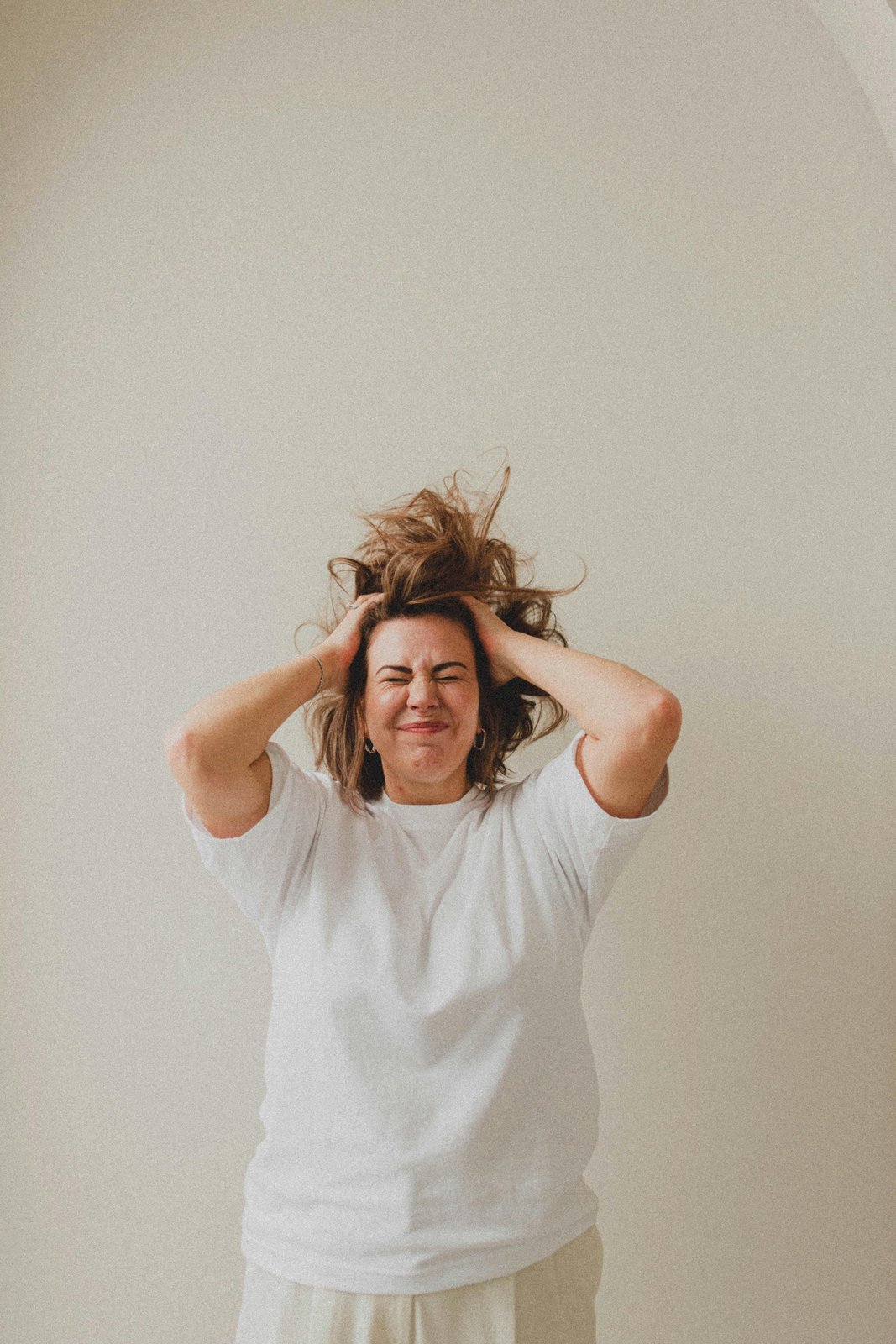A woman with hands in her hair, mid-feeling — the moment of recognizing what no longer fits